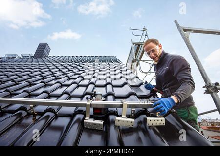 Handwerker, der das Solarpaneelmontagesystem auf einem Dach installiert Stockfoto