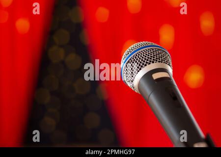 Goiânia, Goias, Brasilien – 12. April 2023: Ein schwarzes Mikrofon auf einer Bühne mit einem verschwommenen roten Vorhang im Hintergrund. Stockfoto