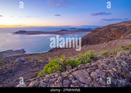 Blick auf die Insel La Graciosa und die Stadt Caleta del Sebo von Mirador del Rio bei Sonnenuntergang, Lanzarote, Las Palmas, Kanarische Inseln, Spanien, Atlantik, Europa Stockfoto