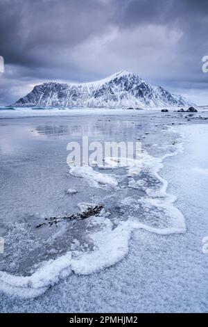 Gefrorene Wellenmuster am Strand von Skagsanden, hinter dem Hustinden Mountain Winter, nahe Flakstad, Flakstadoya, Lofoten Inseln, Nordland County, Norwegen, Sc Stockfoto