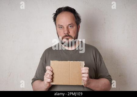 Schmuddeliger Mann mit leerem Pappschild Stockfoto