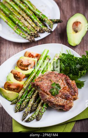 Verglaste grüner Spargel mit Sesam und gegrilltes Schweinekotelett Stockfoto