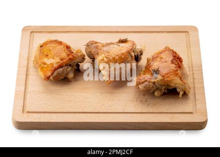 Gebratene Hähnchenschenkel auf Holzschneidplatte isoliert auf weiß mit Schneideweg Stockfoto