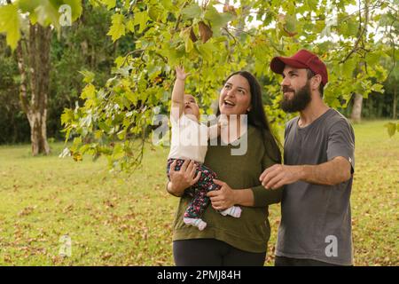 Stolze und glückliche Eltern, die einen Moment mit ihrer Tochter in einer natürlichen Umgebung verbringen. Positive und liebevolle Familie. Stockfoto