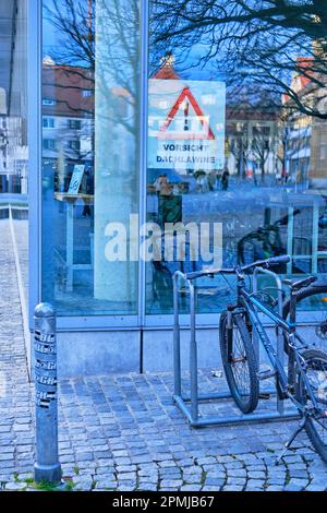 Vorsicht Dachlawine, Warnschild hinter der Glasfassade der Stadtbibliothek am Rathausplatz in Ulm, Baden-Württemberg, Deutschland, Europa. Stockfoto