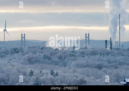 Hängebrücke und Industrie hinter einem eisigen Winterwald Stockfoto