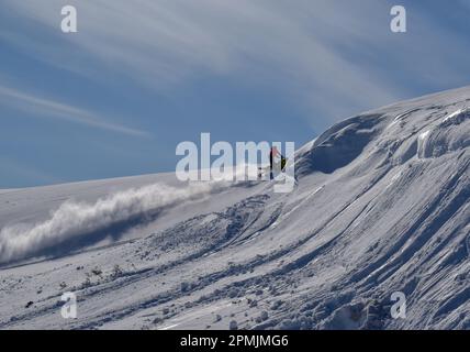 Ein Mann fährt Schneemobil in den Bergen. Schöner Tag in schwedischem Lappland. Kiruna, Nikkaluokta. Stockfoto