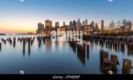 New York, USA - 25. April 2022: Lower Manhattan und ein alter Brooklyn Pier in der Abenddämmerung Stockfoto