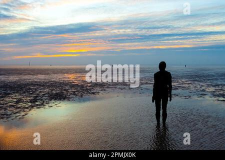 Ein Mann steht an einem Sandstrand mit Blick aufs Meer Stockfoto