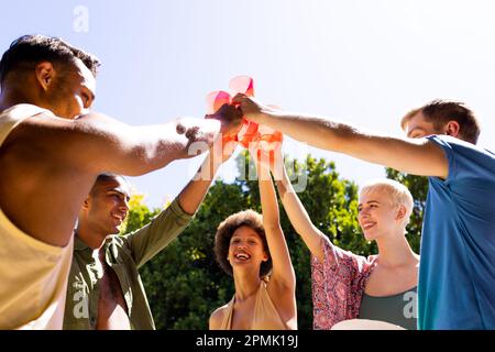 Fröhliche, vielfältige Gruppe von Freunden, die im Garten anstoßen Stockfoto
