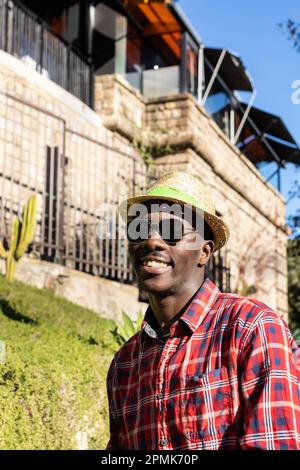 Ein afrikanischer Mann im Urlaub mit Sommerhut und rotem Hemd im botanischen Garten in Barcelona, Spanien Stockfoto