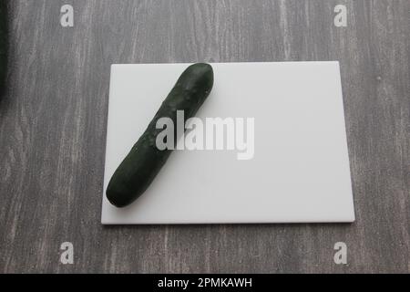 Frische, grüne Gurken auf einem Schneidebrett mit Messer werden für einen nahrhaften Salat oder Saft auf einem Küchentisch zubereitet Stockfoto