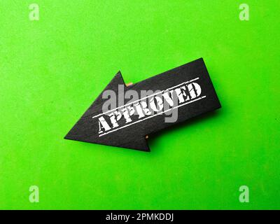 Schwarzer Holzpfeil mit DEM Wort GENEHMIGT auf grünem Hintergrund. Geschäftskonzept. Stockfoto