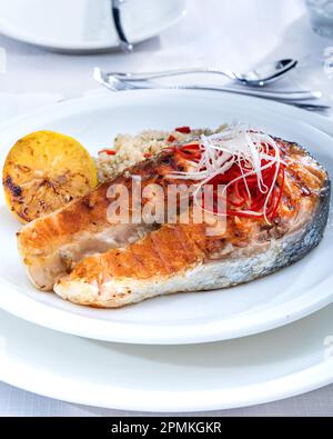 Gesunde Mittagsschüssel mit gegrilltem Lachs, Quinoa und Gemüse. Köstliches Lachssteak auf dem Tisch serviert mit Quinoa. Stockfoto