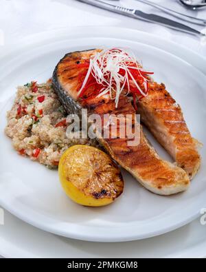 Gesunde Mittagsschüssel mit gegrilltem Lachs, Quinoa und Gemüse. Köstliches Lachssteak auf dem Tisch serviert mit Quinoa. Stockfoto