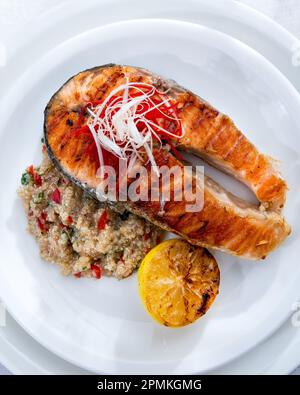 Gesunde Mittagsschüssel mit gegrilltem Lachs, Quinoa und Gemüse. Köstliches Lachssteak auf dem Tisch serviert mit Quinoa. Stockfoto