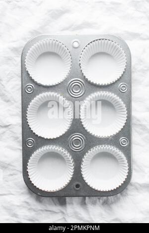 Silberne Cupcake-Pfanne zum Zubereiten von Cupcakes und Muffins mit weißen Einlagen. Sechs Muffin-Pfanne Stockfoto