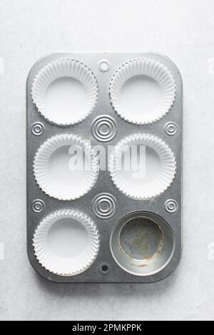 Silberne Cupcake-Pfanne zum Zubereiten von Cupcakes und Muffins mit weißen Einlagen. Sechs Muffin-Pfanne Stockfoto