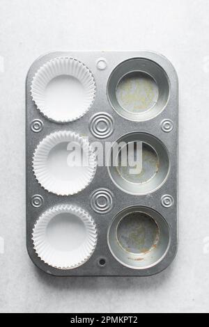 Silberne Cupcake-Pfanne zum Zubereiten von Cupcakes und Muffins mit weißen Einlagen. Sechs Muffin-Pfanne Stockfoto