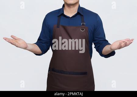 Asiatischer Mann mit Schürze in lässiger, stilvoller Kleidung, hohe Standposition mit offenen Armen, kann einladend oder wundervoll sein, kein Gesicht isoliert Weiß b Stockfoto