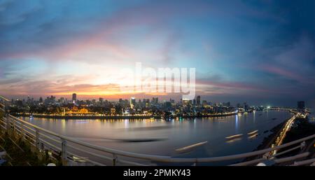 Das goldene Nachglühen über Kambodschas Hauptstadt, das geschäftige Flussufer und berühmte Wahrzeichen und der Königspalast, während die untergehende Sonne von hinten sinkt Stockfoto