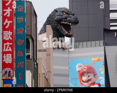 TOKIO, JAPAN - 12. April 2023: Statue von Godzilla in einem Toho-Kino in Shinjuku mit einem Poster für die Super Mario Bros Film darauf. Stockfoto