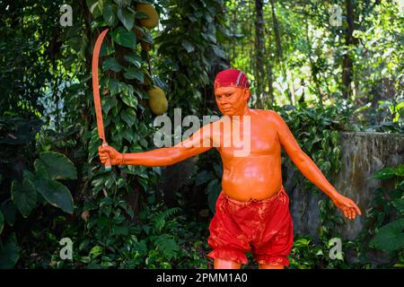 Porträt eines Hindu-Anhängers, der am letzten Tag des Bangla-Monats am Stadtrand von Dhaka in Munshigonj an einem Festival namens Lal Kach (Rotes Glas) teilnimmt. Das Festival ist der Verehrung von Lord Shiva und Parvati gewidmet. Es wird angenommen, dass eine Gruppe von Soldaten unter Shiva auf der Erde auftaucht, mit der Mission, die Mächte des Bösen abzuwehren. Diese Soldaten, die im göttlichen Licht Shivas leuchten, marschieren zu nahe gelegenen Tempeln. Das alles ist Teil einer sehr langen Tradition, die Hunderte von Jahren zurückreicht. Die Hindus, vor allem die Jungen, malen sich rot an, nehmen Schwerter und holen Prozessi heraus Stockfoto