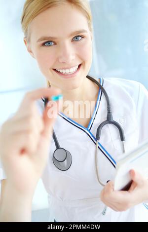 Ich verschreibe Ihnen das beste Arzneimittel. Porträt einer hübschen Krankenschwester, die eine blaue Pille hält. Stockfoto