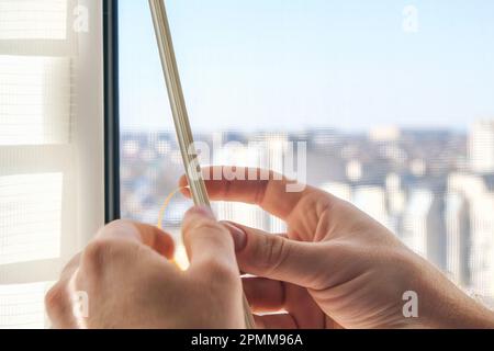 Der Mann wischt den Fensterrahmen mit einem Entfetter ab und klebt ein Gummidichtungsband zur Schalldämmung, Windschutz und Wetterschutz darauf. Stockfoto