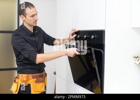 Nicht mit der Reparatur verzögern. Nahaufnahme der reparateur Backofen Prüfung mit einem Schraubendreher in der Küche im Koffer Stockfoto