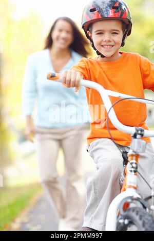 Sieh mich an, mom. Eine Mutter, die ihrem Sohn beim Fahrradfahren zusieht. Stockfoto