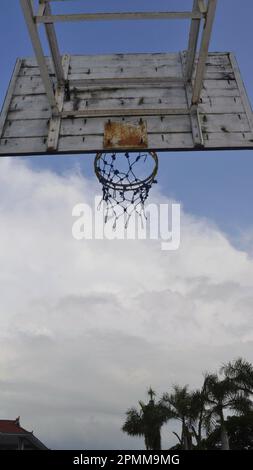 Basketballring von hinten mit blauem Himmel und Bäumen als Hintergrund. Basketballfeld im Freien. Stockfoto