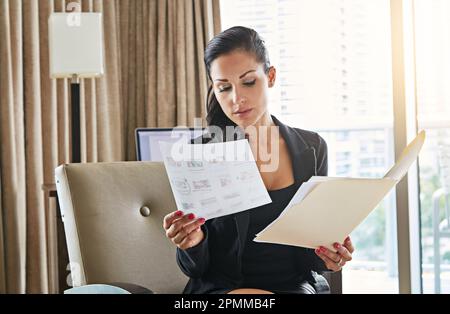 Erstklassiges Geschäft. Eine junge Geschäftsfrau, die in ihrem Hotelzimmer arbeitet. Stockfoto