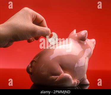 1991 HISTORISCHE FRAUEN LEGEN 2 DEUTSCHE-MARK-MÜNZE IN DIE PIGGY BANK Stockfoto