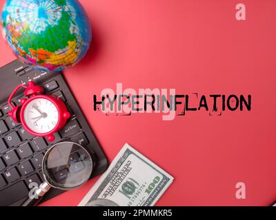 Top View Uhr, Lupe, Erdkugel und Banknoten mit dem Wort HYPERINFLATION. Stockfoto