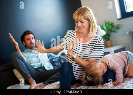 Müde Mutter und Vater, die auf der Couch sitzen, fühlen sich genervt, erschöpft, stressig mit dem kleinen Mädchen. Stockfoto