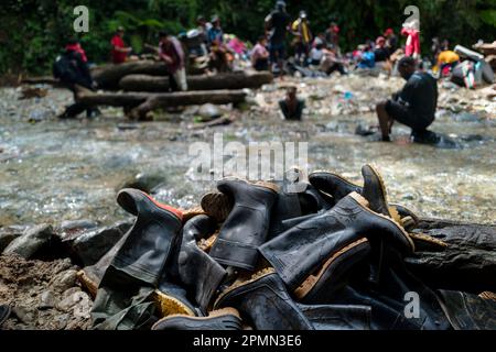 Am Ufer des Flusses im Dschungel der Darién-Lücke zwischen Kolumbien und Panamá liegt ein Haufen von abgenutzten Gummistiefeln, die von Migranten weggeworfen wurden. Stockfoto