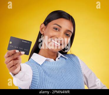 Kreditkarte, Porträt und indische Frau mit gelbem Hintergrund für Bank, Investition und Bezahlung im Studio. Bankmodell, Finanzen und glückliches Mädchen Stockfoto
