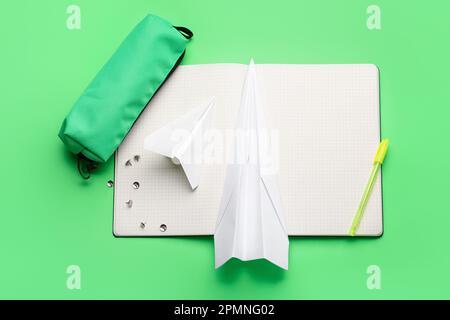 Komposition mit Büromaterial und Papierflugzeugen auf grünem Hintergrund Stockfoto