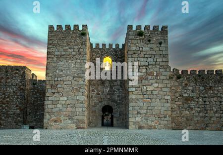 Haupttor des Schlosses und der Festung Trujillo, Caceres, Spanien aus dunklem Stein, zwei zerkleinerte Türme und Nische der Jungfrau im Zentrum beleuchtet Stockfoto