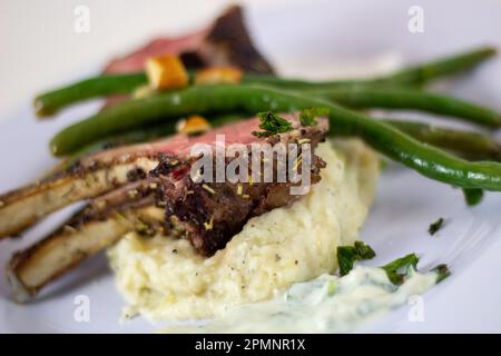 Nahaufnahme von Frenched Lamm mit Kartoffelpüree und grünen Bohnen Stockfoto