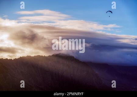 Gleitschirmfliegen über Berggipfeln in der Dämmerung bei Honolulu; Oahu, Hawaii, Vereinigte Staaten von Amerika Stockfoto