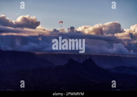 Gleitschirmfliegen hoch über Berggipfeln in der Dämmerung bei Honolulu; Oahu, Hawaii, Vereinigte Staaten von Amerika Stockfoto