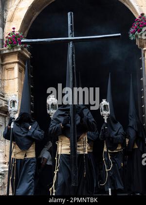 Die Buhnen tragen schwarze, kegelförmige Kapuzen und tragen Holzkreuze aus der St. Mary Major Church während einer Heiligen Woche oder Semana Santa Prozession am Karfreitag, 6. April 2023 in Ronda, Spanien. Ronda, die sich im 6. Jahrhundert v. Chr. niedergelassen hat, hält seit über 500 Jahren Heilige Woche-Prozessionen ab. Kredit: Richard Ellis/Richard Ellis/Alamy Live News Stockfoto