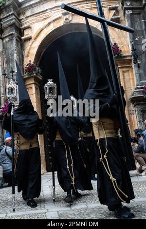 Die Buhnen tragen schwarze, spitz zulaufende Kapuzen und tragen ein Holzkreuz aus St. Mary Major Church während einer Heiligen Woche oder Semana Santa Prozession am Karfreitag, 6. April 2023 in Ronda, Spanien. Ronda, die sich im 6. Jahrhundert v. Chr. niedergelassen hat, hält seit über 500 Jahren Heilige Woche-Prozessionen ab. Kredit: Richard Ellis/Richard Ellis/Alamy Live News Stockfoto