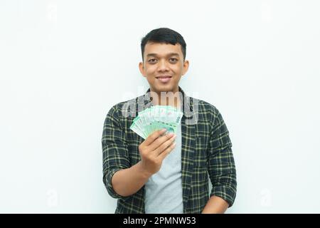 Ein junger asiatischer Mann zeigt indonesisches Rupiah-Geld Stockfoto