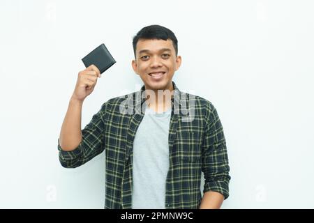 Ein junger asiatischer Mann lächelt, während er die schwarze Brieftasche in der Hand hält Stockfoto