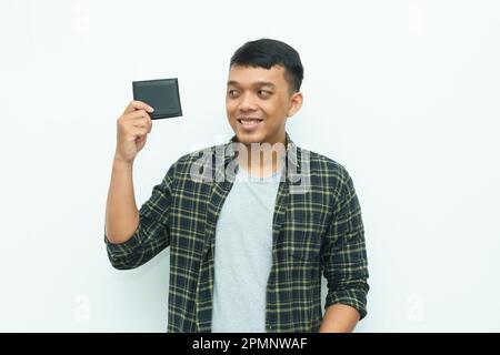 Ein junger asiatischer Mann lächelt, während er die schwarze Brieftasche in der Hand hält Stockfoto