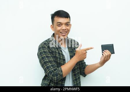 Ein junger asiatischer Mann, der lächelt, während er auf die schwarze Brieftasche zeigt Stockfoto
