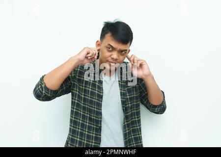 Ein junger Asiate, der sich die Ohren mit den Fingern bedeckt und Lärm vermeidet Stockfoto